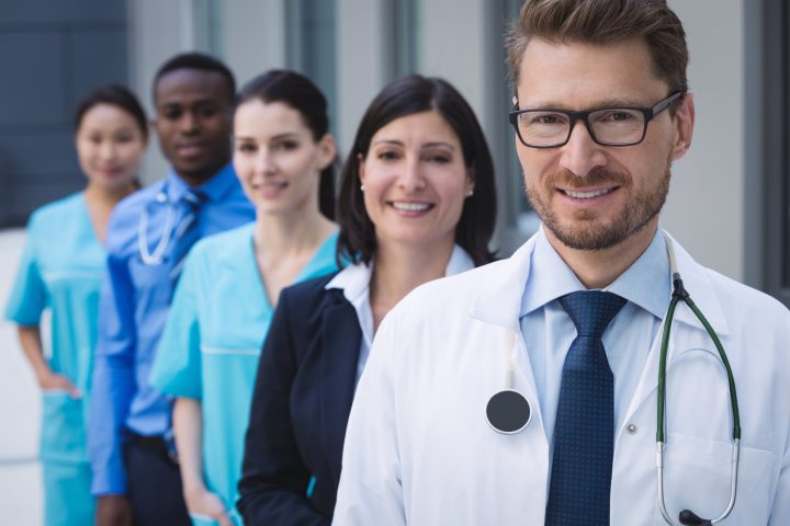 Portrait of smiling doctors standing in row at hospital premises Portrait of smiling doctors standing in row at hospital premises